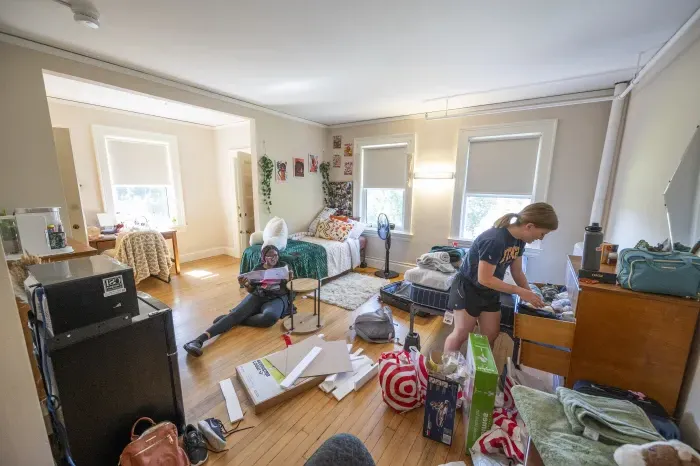 Two students organize their room and put furniture together.